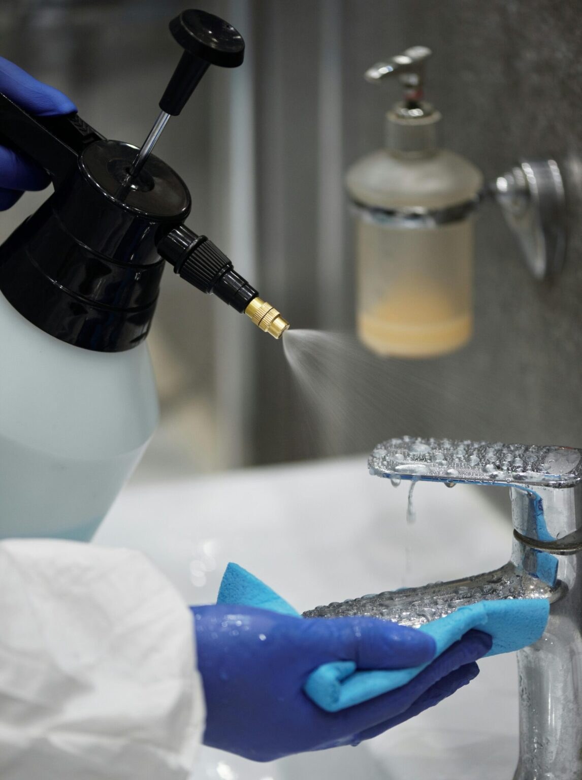 Cleaner wiping a kitchen sink with a blue glove