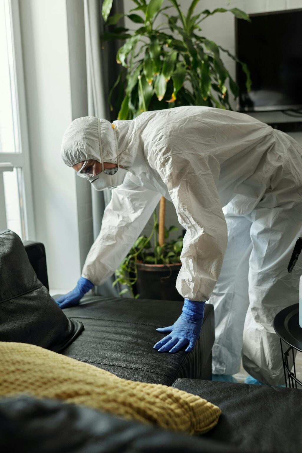 Technician in protective gear applying electrostatic disinfection