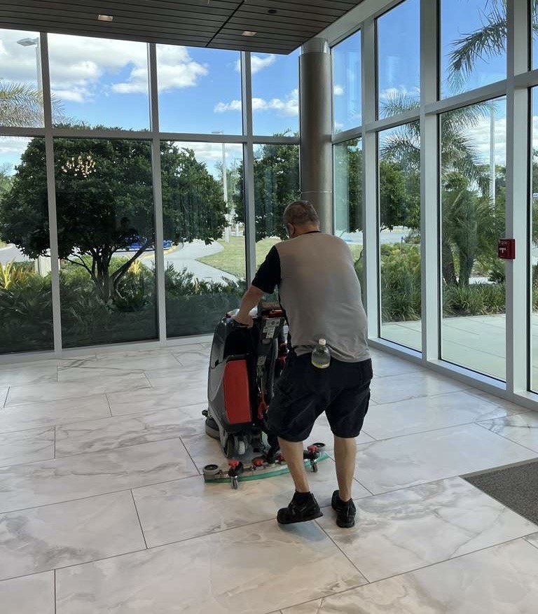 Dust Busters cleaner running a floor scrubber in a commercial lobby